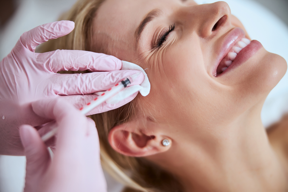 Smiling lady lying with her eyes closed during the rejuvenation injection
