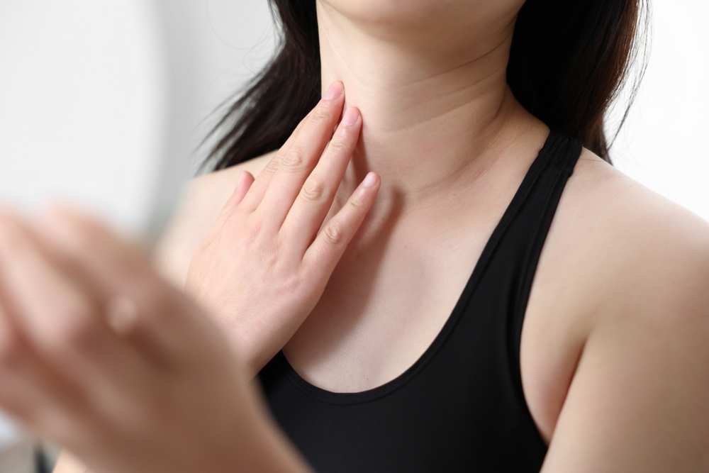 A woman looking in the mirror while touching her neck wrinkles.